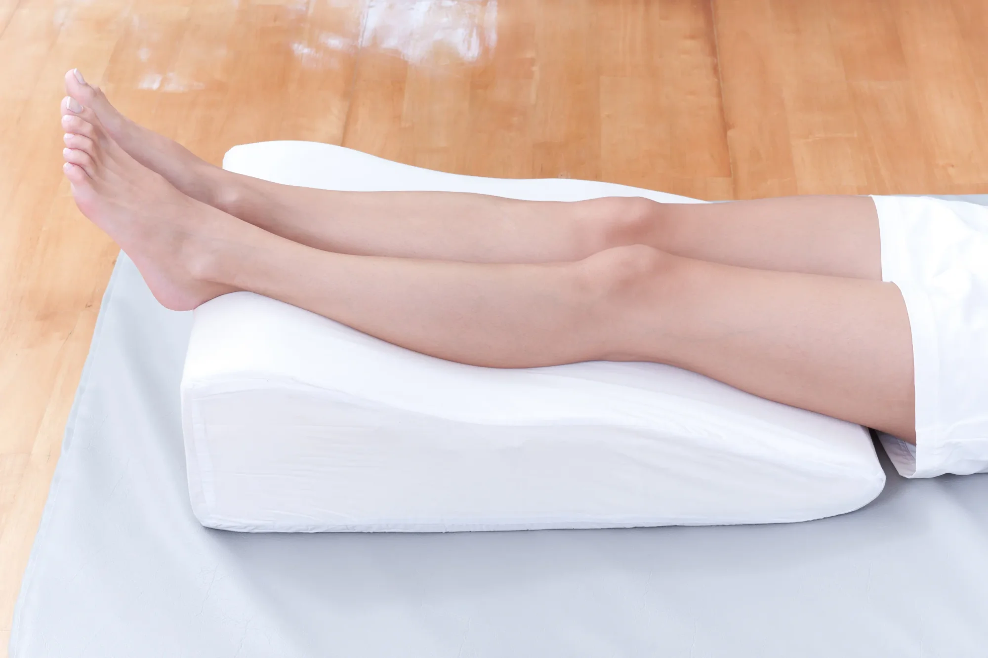 A woman's legs elevated on a pillow to increase circulation and alleviate edema swelling.
