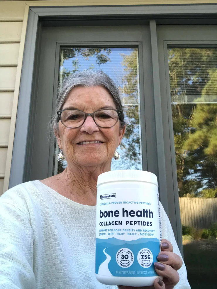 An older woman holding a container of NativePath Bone Health Collagen Peptides