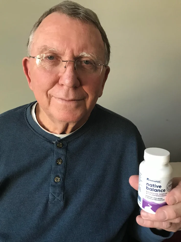 An older man holding a bottle of NativePath Native Balance