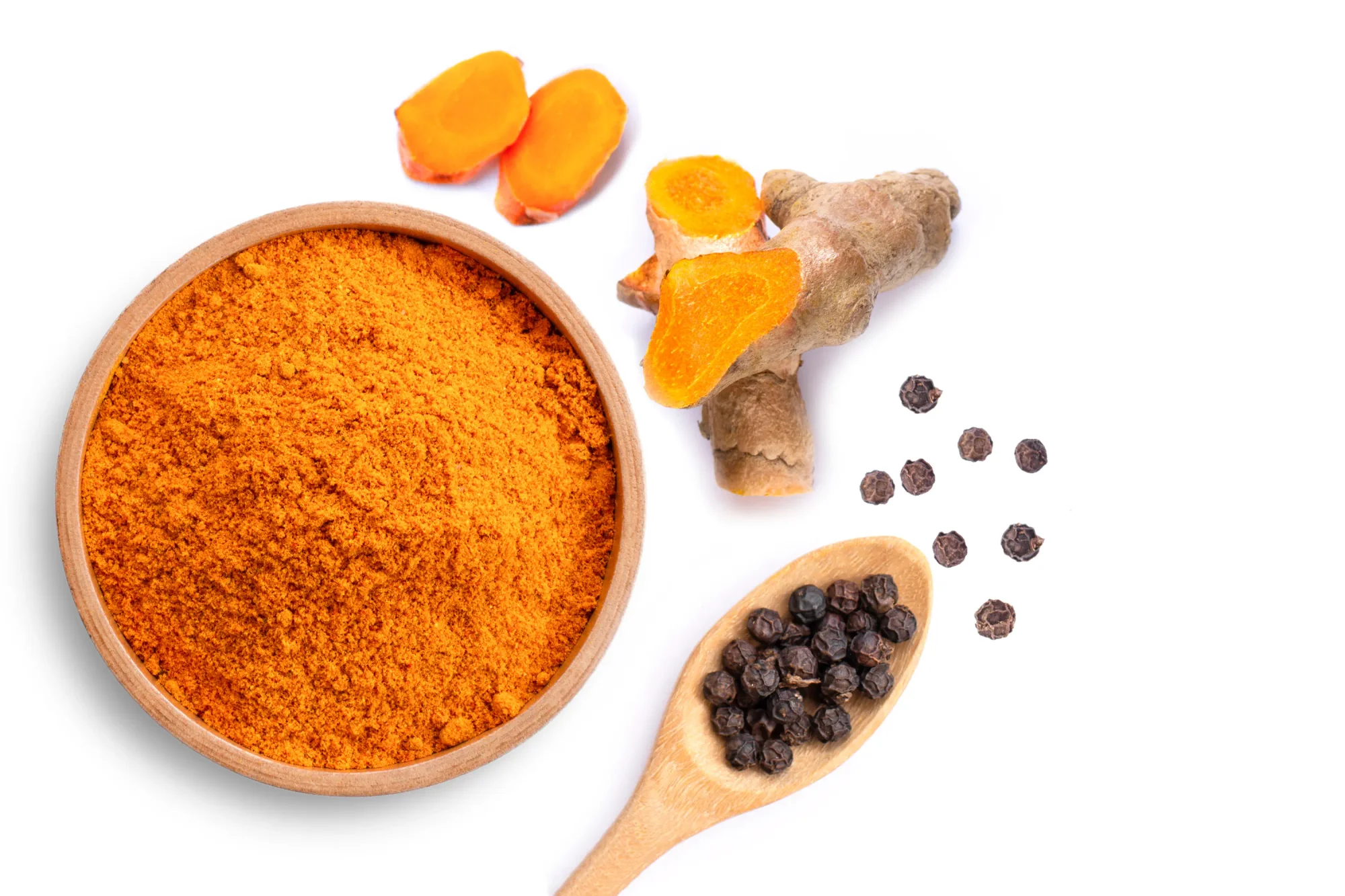 Curcumin powder (turmeric ground, turmeric, Curcuma) in a wooden bowl and black peppercorns in a spoon isolated on white background. Health benefits and antioxidant food concept. Top view. Flat lay.