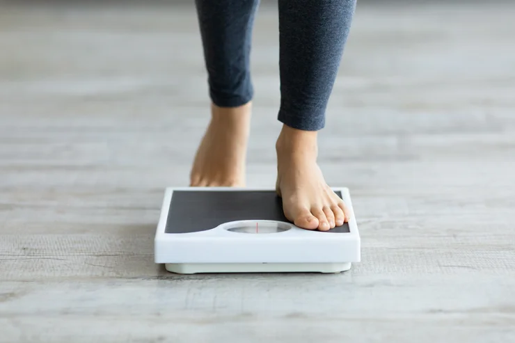 A woman's feet stepping on a scale.