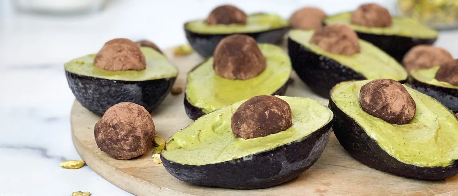 Several vanilla bean avocado ice creams in avocado skins with a chocolate truffle as a pit.  