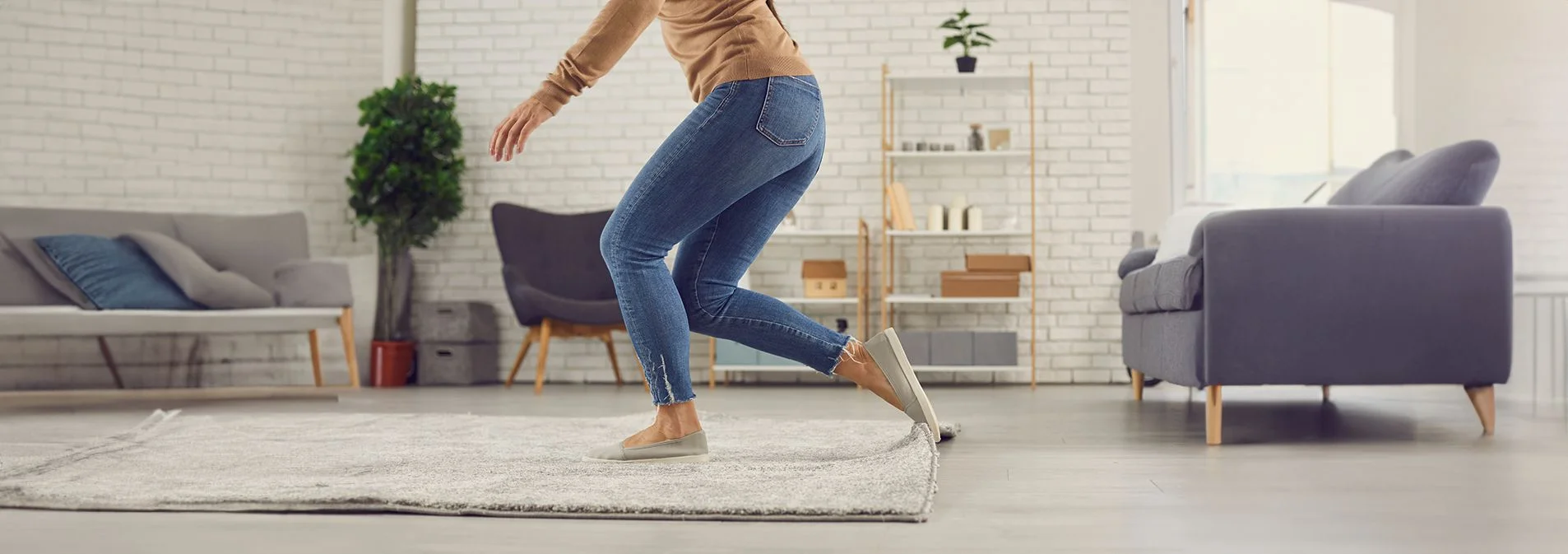 A side photo of a woman tripping and falling over a rug. 