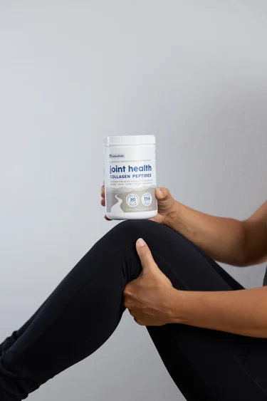 A container of NativePath Joint Health Collagen on a woman's bent knee