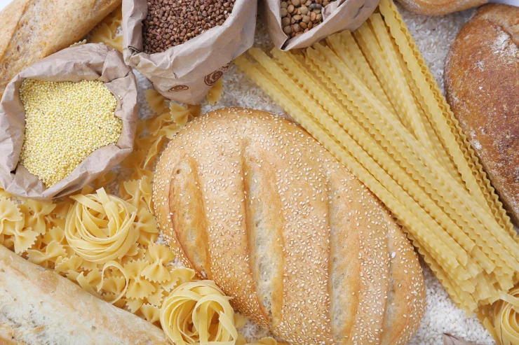 Close-up shot of bread, pasta noodles, and grains.