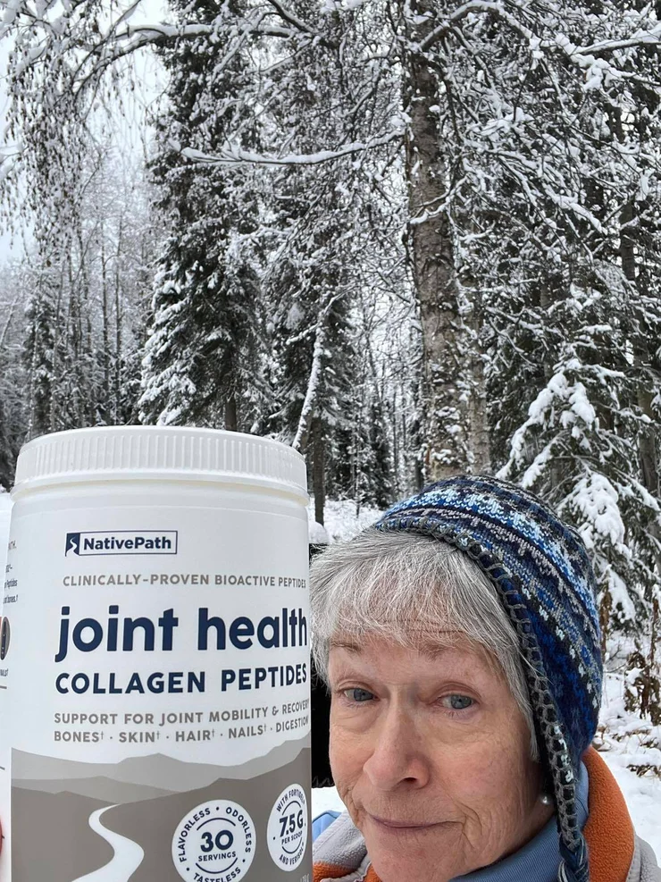 An older woman in the snow holding a jar of NativePath Joint Health Collagen