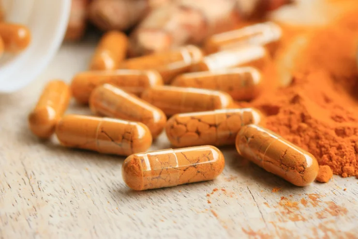 A close up image of turmeric powder and capsules