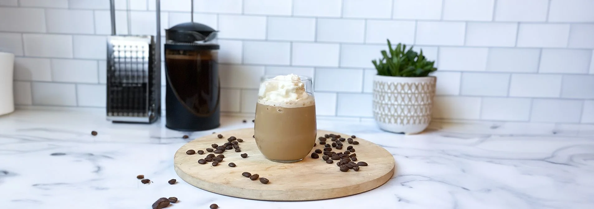 Front view shot of the Blended Vanilla Frappuccino on a circular wooden board with coffee beans around it