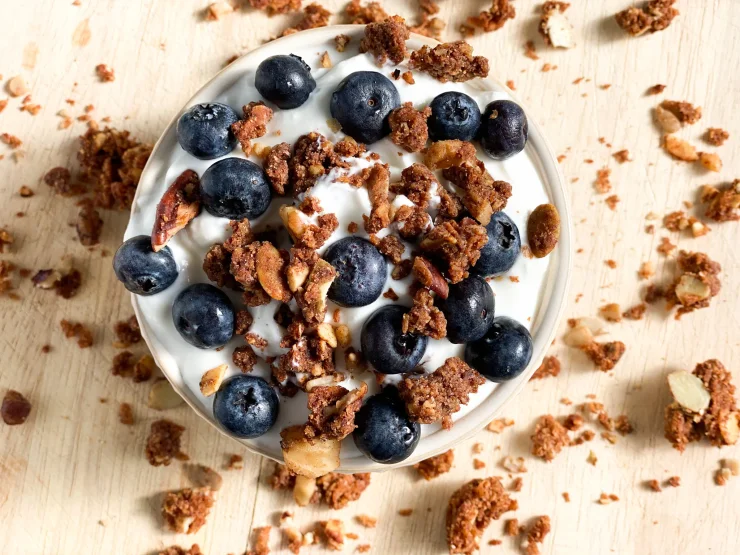 Bowl of yogurt topped with Native Nola and fresh blueberries