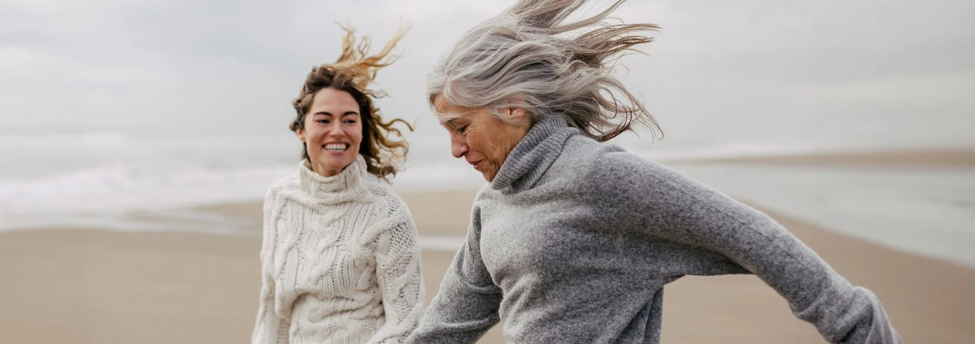 Older woman and her adult daughter enjoying a walk on the beach