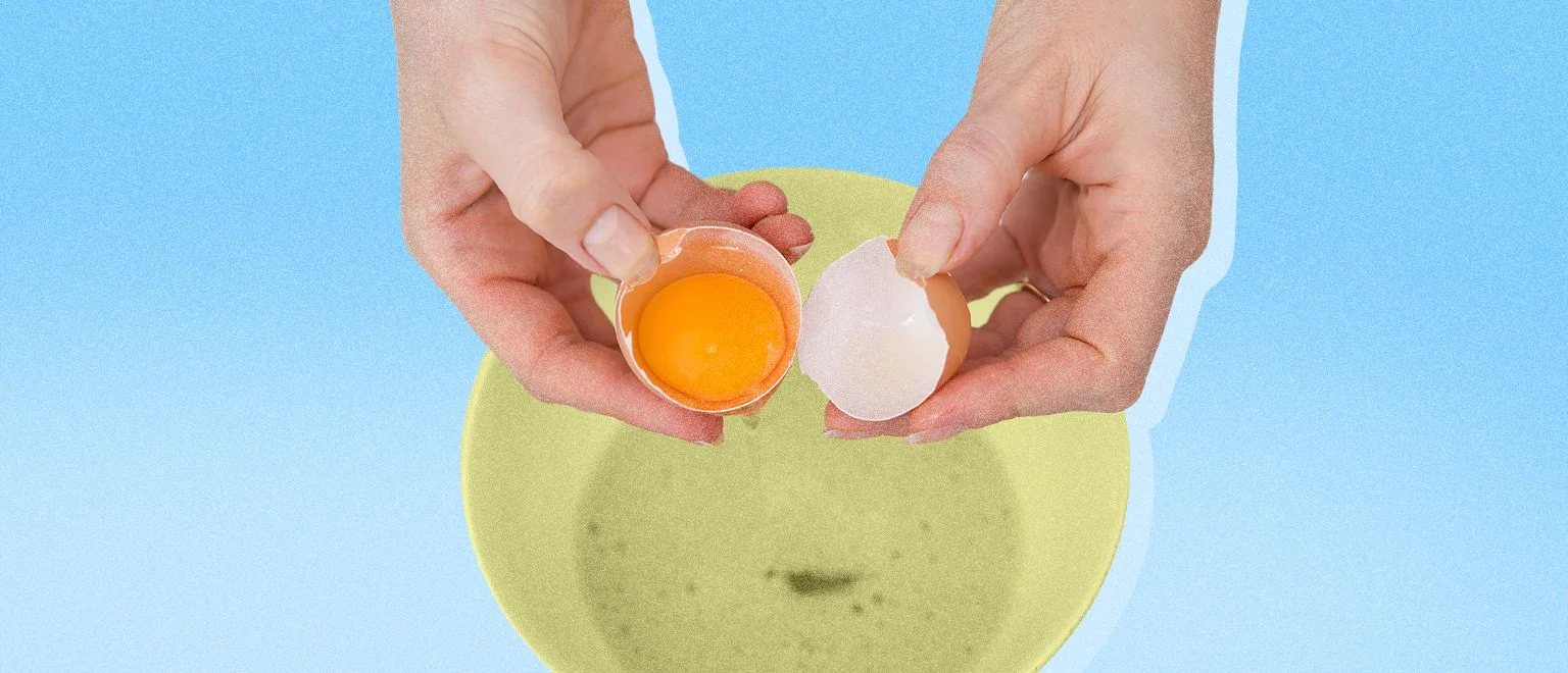 Overhead shot of a woman's hands cracking an egg into a bowl