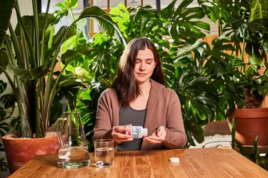 A woman taking NativePath Antarctic Krill Oil with plants in the background