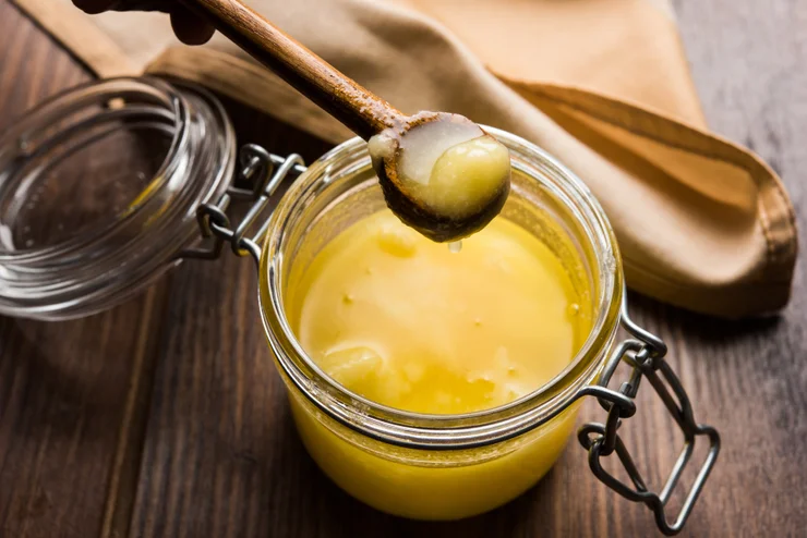 A jar of grass-fed ghee with a wooden spoon