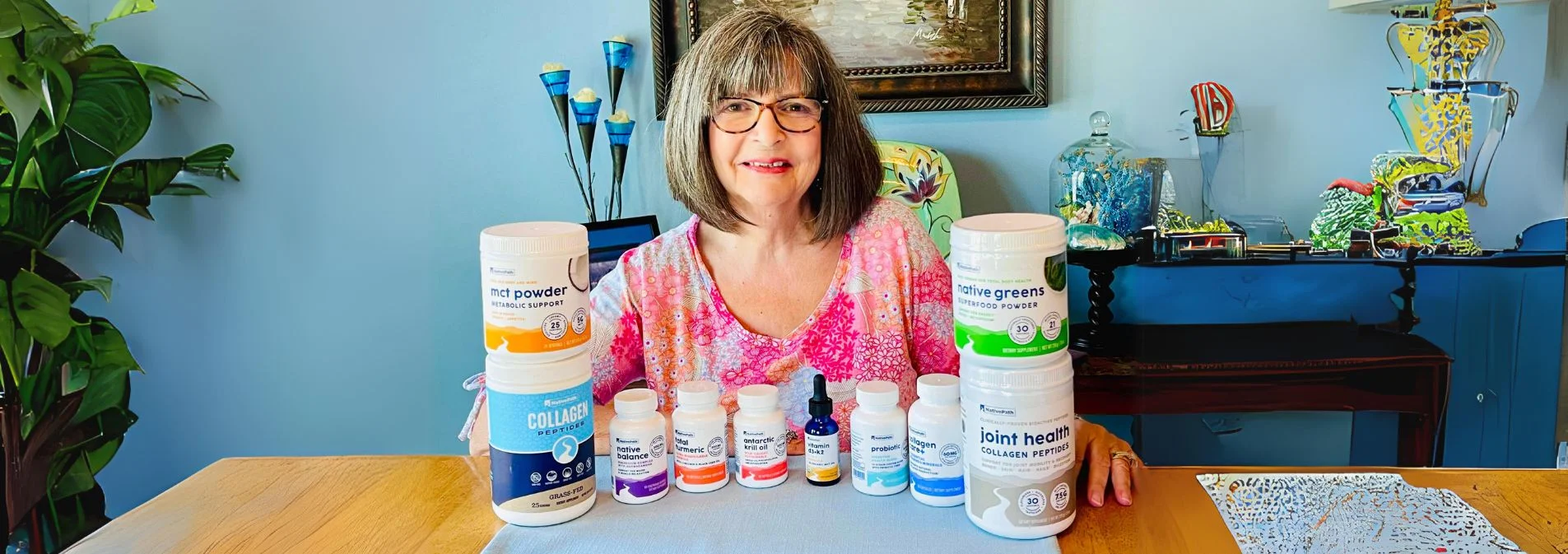 An older woman sitting at a table with a stack of NativePath supplements