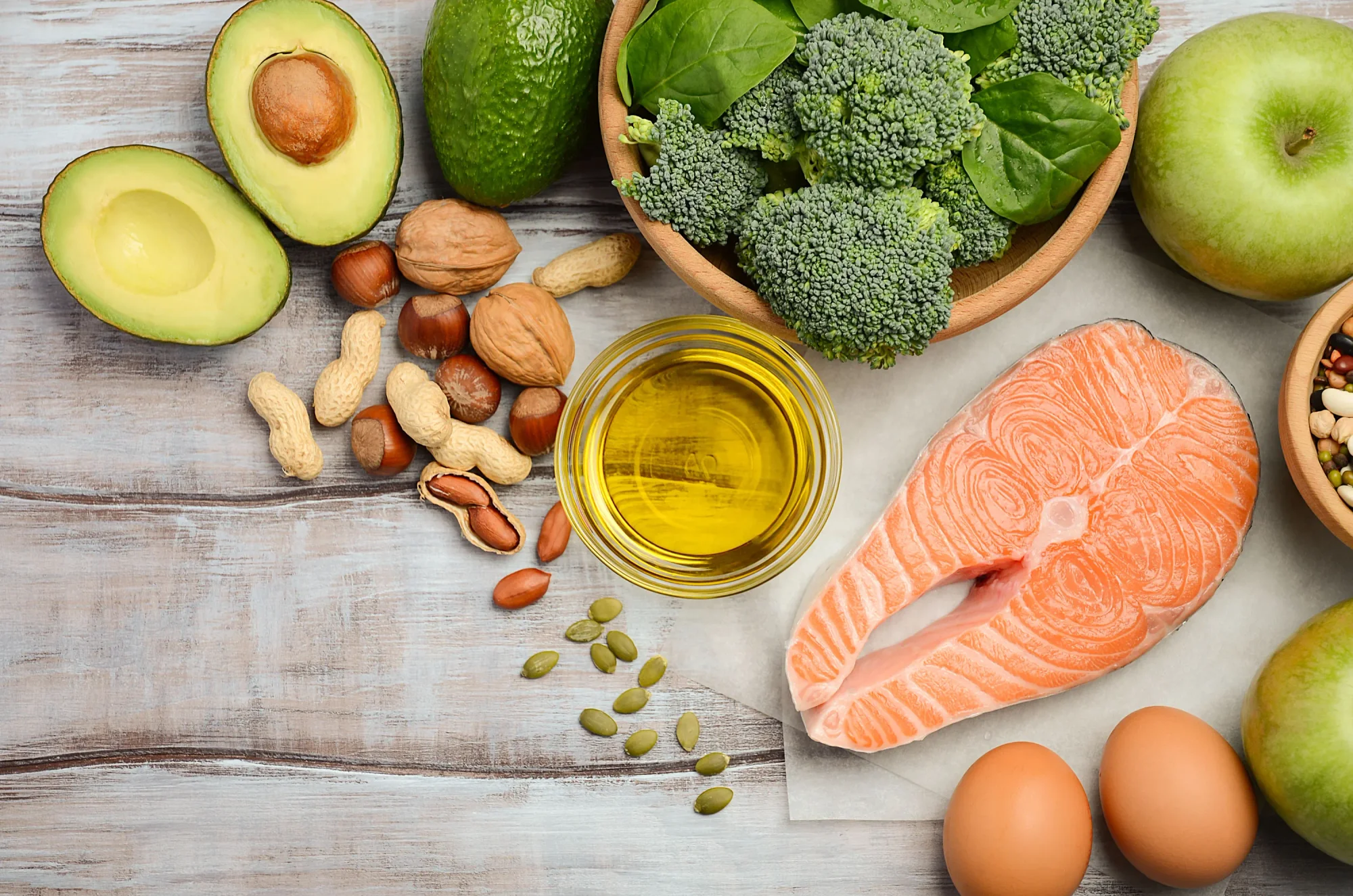 Selection of whole foods with omega-3s: salmon, eggs, nuts, seeds, avocado, olive oil.