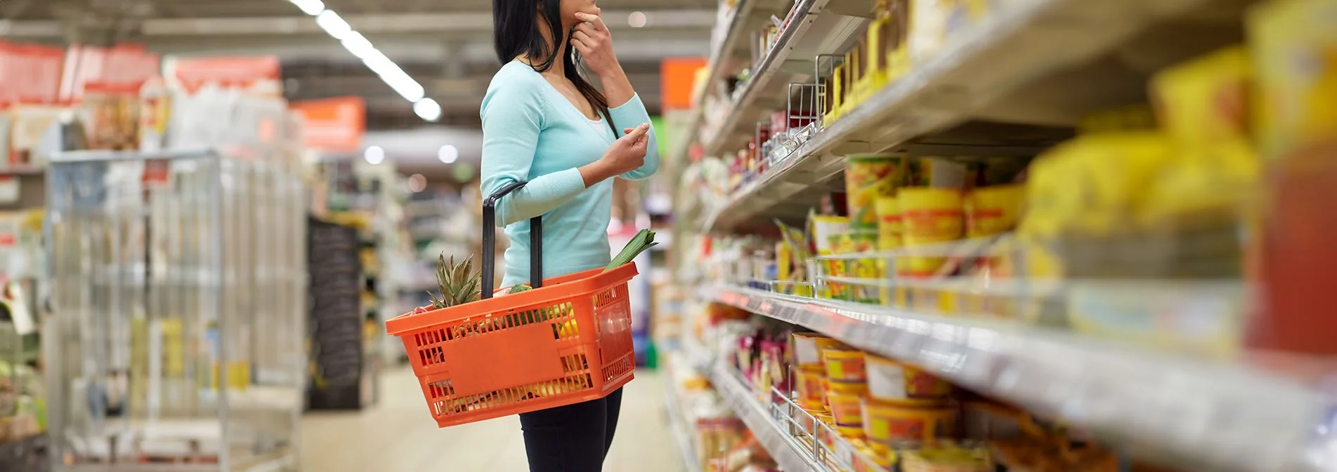 A woman looking confused while looked at food on a grocery shelf