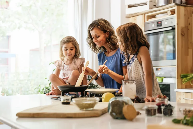 Little sisters cooking with her mother in the kitchen. Infant Chef Concept.