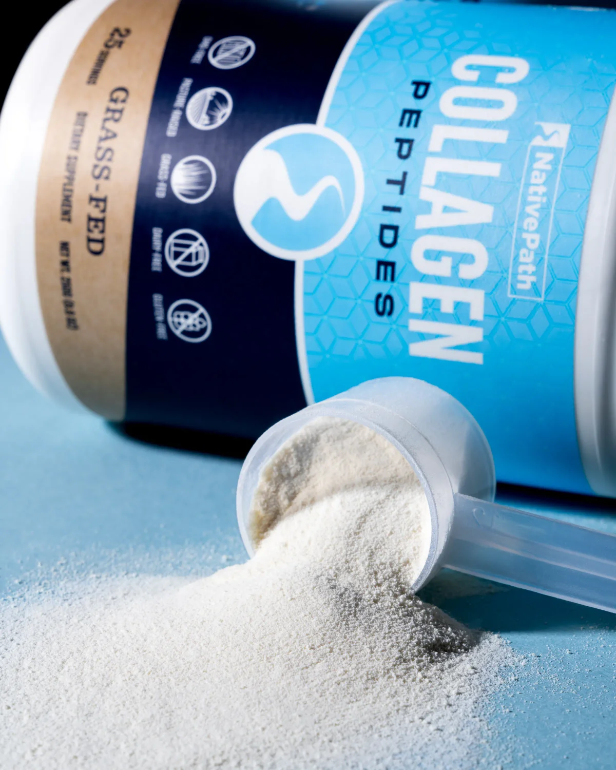 Jar of NativePath Collagen with scoop tipped over pouring out collagen powder