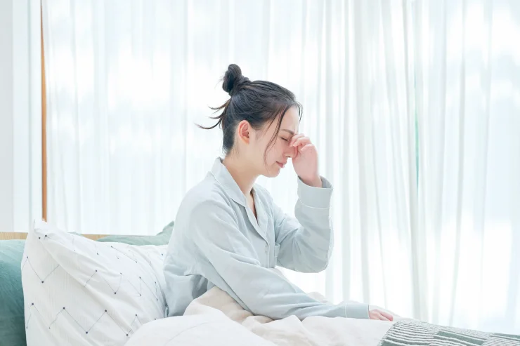 Brunette haired woman in bed suffering from brain fog and loss of motivation.