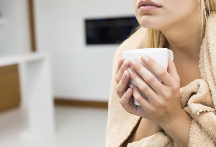 Midsection of young woman holding coffee mug in house