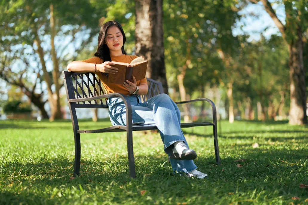A woman sitting on a bench in the park in spring reading a book