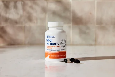 A bottle of NativePath Total Turmeric with three softgels next to it