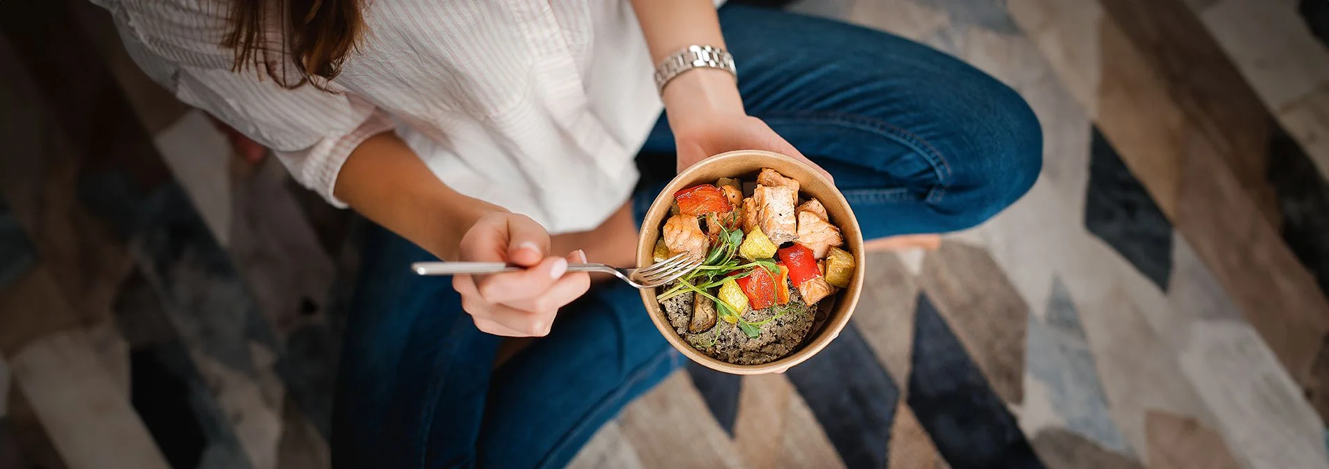 An overhead shot of a woman holding a bowl of food