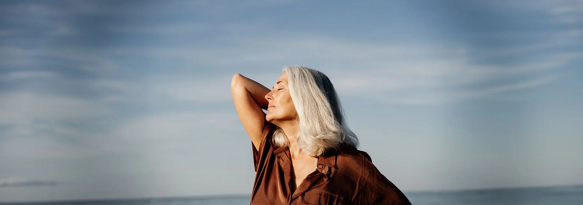 A close up of an older woman enjoying the sunshine at the beach