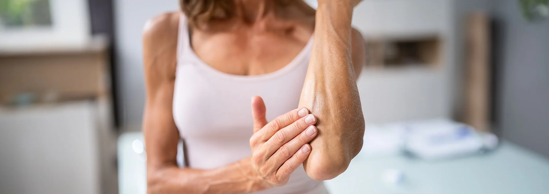 An older woman rubbing lotion on dry skin near her elbow