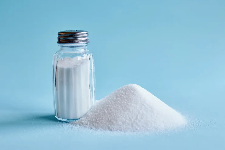 Salt shaker with a pile of salt next to it