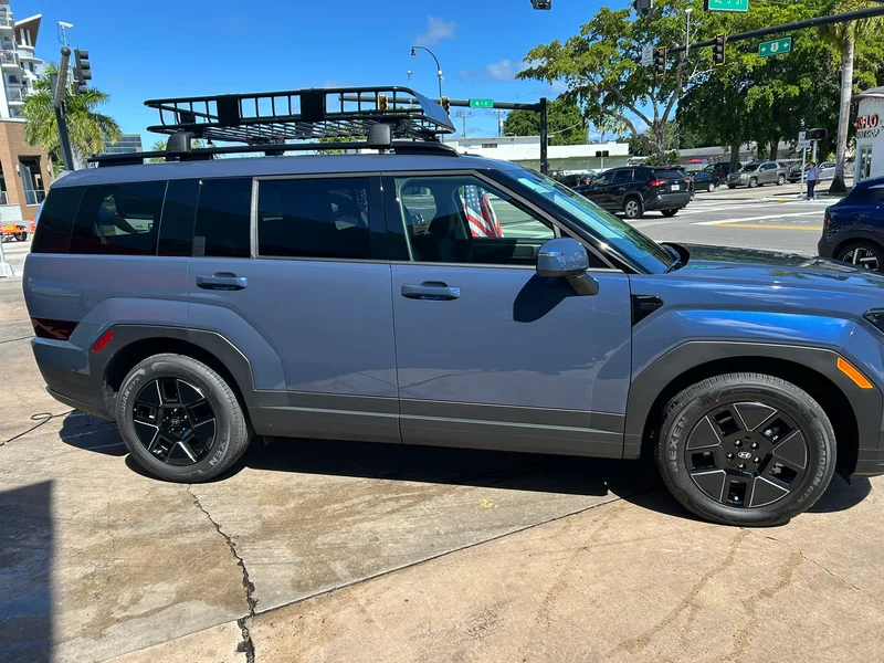 Grey SUV with a roof rack parked on a city street
