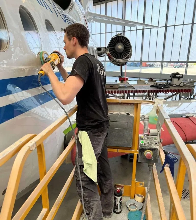 Technician polishing an aircraft fuselage from a hangar work platform