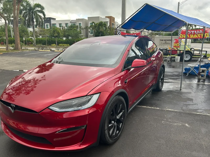Red Tesla Model X parked beside a detailing canopy