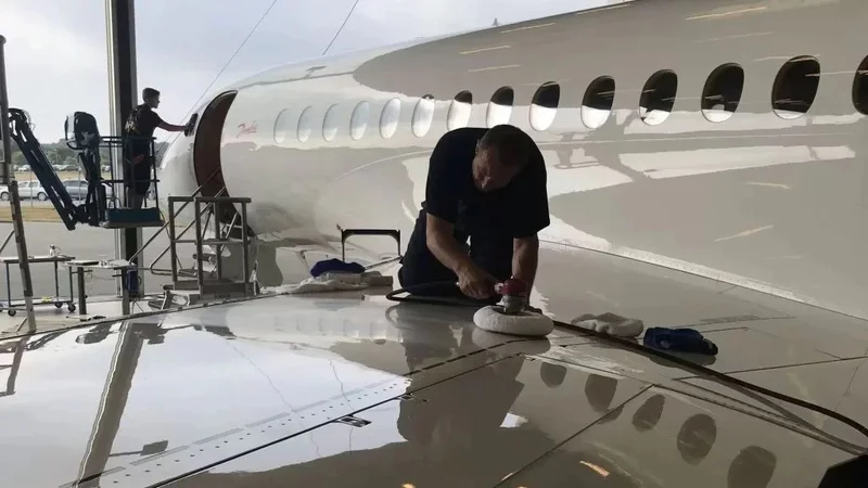 Technician buffing a private jet fuselage in a hangar