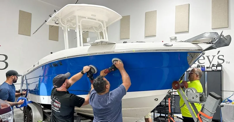 Technician buffing a blue boat hull with a dual-action polisher