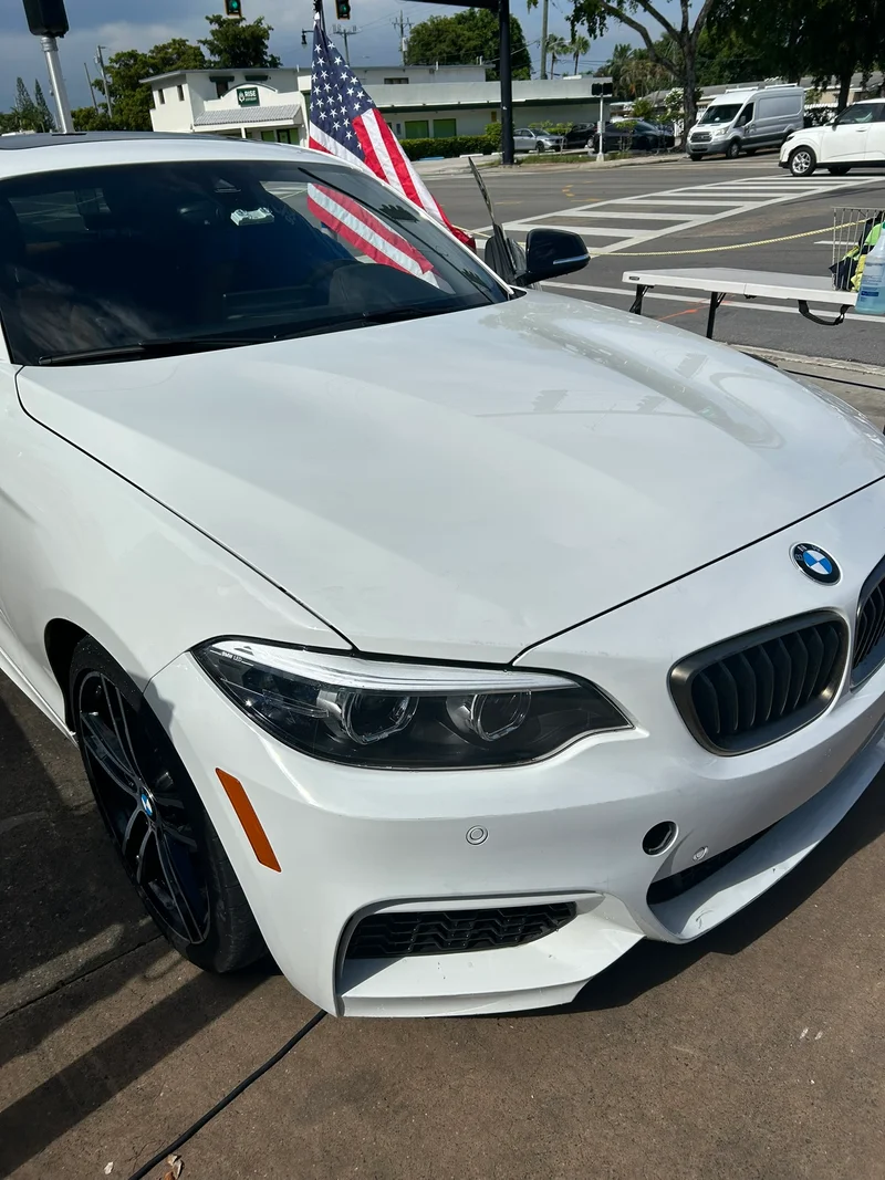 White BMW coupe with an American flag at the wash