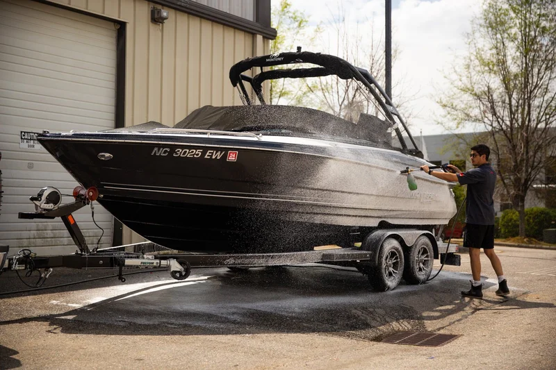 Pressure washing a black boat on a trailer