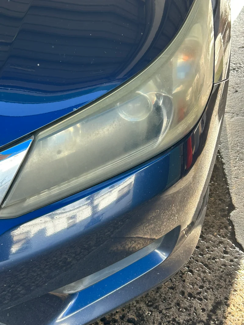 Hazy headlight on a blue sedan before restoration
