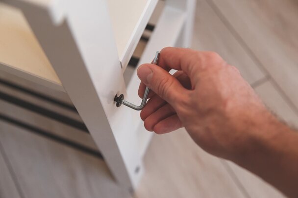 Closeup of hand screwing hex bolt into shelving