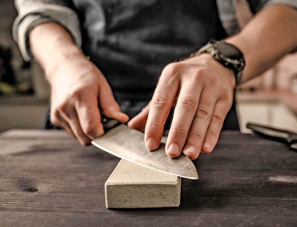 Hands sharpening a blade on a counter