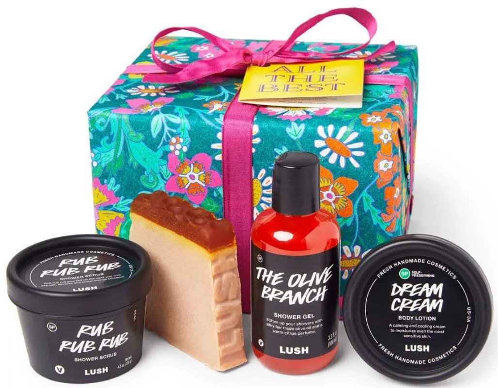 Dark breakfast gift set featuring a bath bomb, body butter, and a candle arranged elegantly on a wooden surface.
