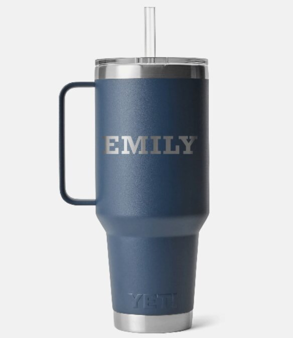 A navy blue insulated Yeti travel mug with a handle, straw, and silver lid. The name "Emily" is engraved in white capital letters on the front.