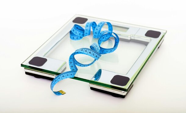 A scale displaying a measuring tape coiled on top, indicating a focus on weight and measurement.