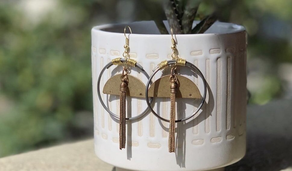 Earrings with gold tassels and half-moon shapes on a white planter