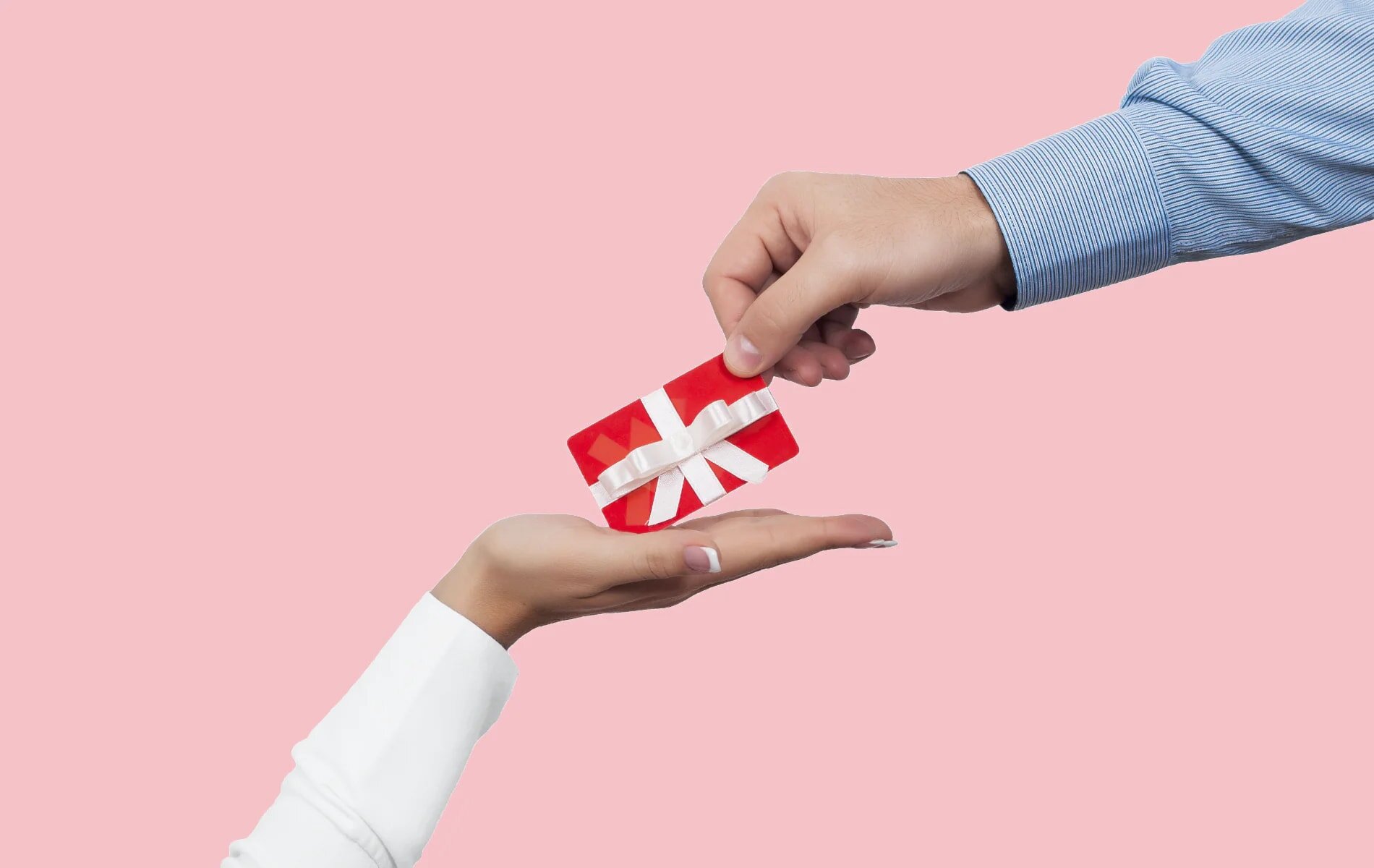 A man presents a gift to a woman against a pink background, capturing a moment of joy and celebration.