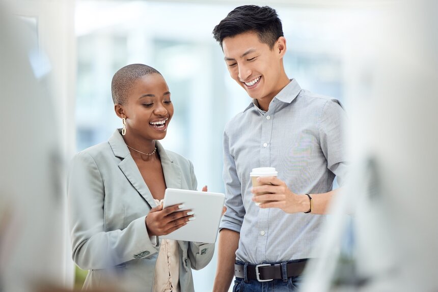 Two men at a table with laptops, surrounded by decorated Christmas trees in a festive setting.