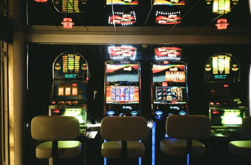 A roulette wheel in a casino as a hand holds a ball, ready to spin. Four people in formal attire watch, displaying anticipation and excitement.