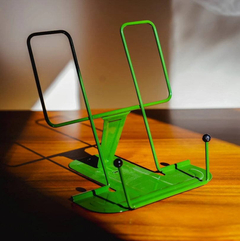 A green metal stand positioned on a wooden table, highlighting a contrast between materials.