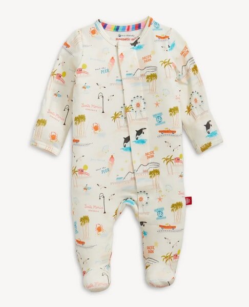 Baby onesie with a beach and ocean theme featuring palm trees, surfboards, crabs, and Route 66 signage on a cream background. Cozy and playful design.