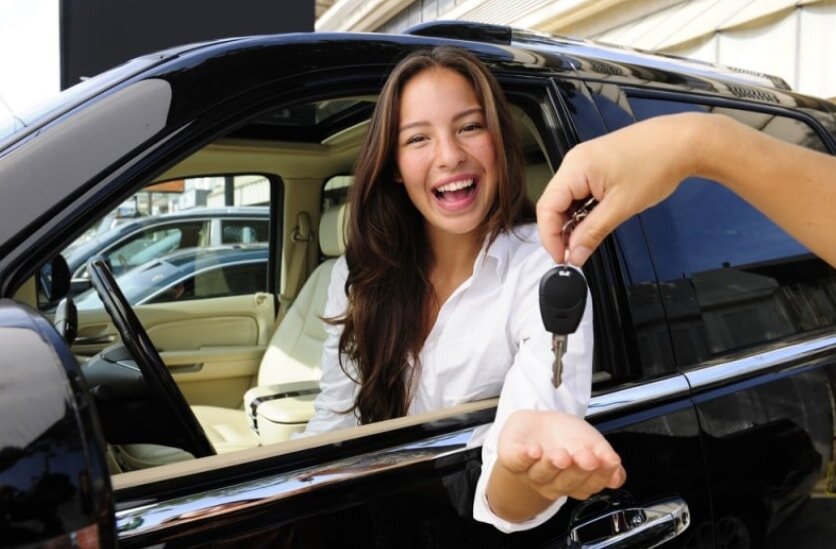 A woman holds a car key, smiling as she prepares to unlock her vehicle.  